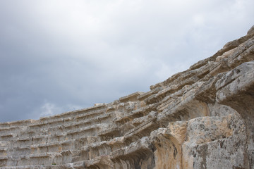 Close up of ancient carved stone steps of Roman theater in Jerash Jordan. Overcast sky is seen above. Photographed from below.
