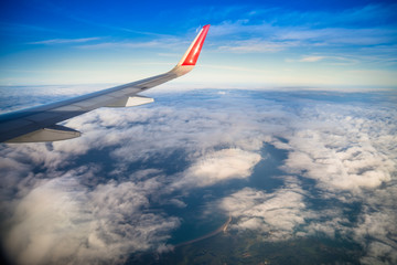 Plane wing on the sky with sunset and cloud, aerial view from airplane window.