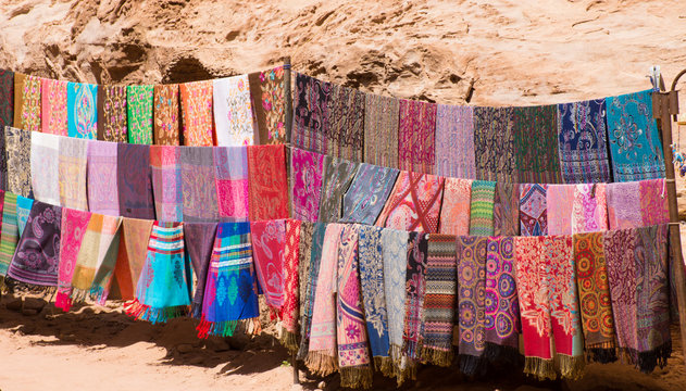 Colorful scarves or pashminas at an outdoor souvenir stand in Petra Jordan. Woven scarves and shawls have multiple designs and patterns in a rainbow of colors.