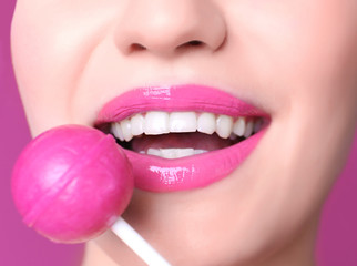 Face of beautiful young woman with lollipop on color background, closeup