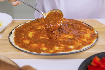 Female's hand pouring tomato sauce