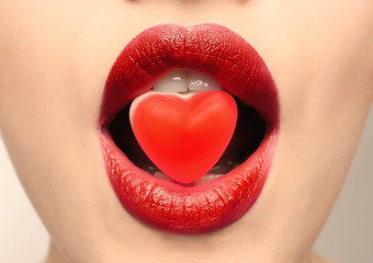 Beautiful young woman with candy in mouth, closeup