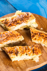 Slices of baked cheese pie served on the retro rustic round wooden board