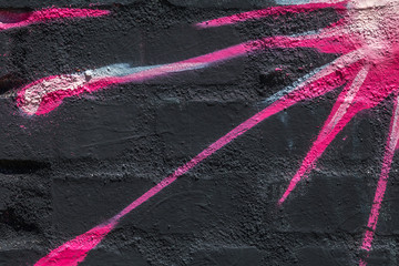 Close up of blue, white, pink, red and black sunburst graffiti on a brick wall