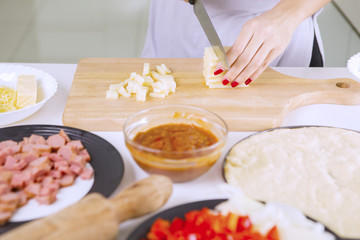 Obraz na płótnie Canvas Woman's hand slicing pile of cheese
