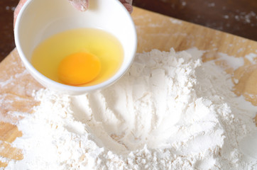 Pouring egg yolk mixing with flour to making bread or cake,bakery cooking