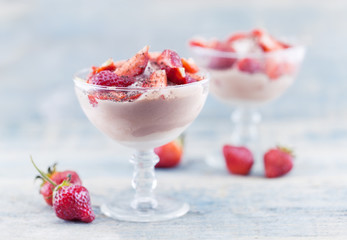 Sweet dessert from cheese and yogurt with fresh ripe strawberry in a glass jar, on rustic wooden background. Selective focus