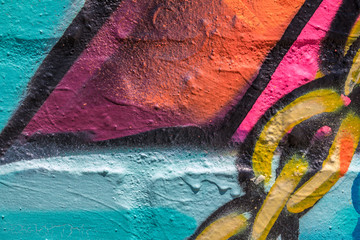 Close up of red, blue, pink, orange, yellow and black graffiti with chain links on a brick wall