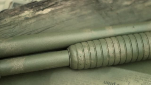 Camera pans over spray painted camouflage shotgun on table