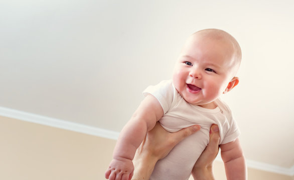Happy infant baby girl being held up in the air