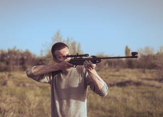 The man takes aim at the target with a sniper strikeball rifle. Retro toning colors. Selective Focus