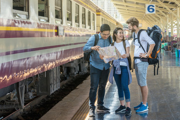 Multiethnic Travellers are looking at train and holding the map with happiness action at the train station, Travel and transportation concept