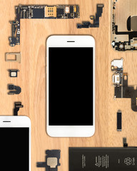 Flat Lay (Top view) of smartphone is surrounded by its own components on wooden background in 4:5...