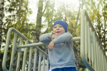 Happy kid enjoying active summer vacation. Adorable little child, blond cute toddler boy, having fun outdoors climbing on playground in the park on a sunny day