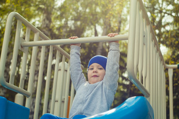 Obraz premium Little toddler boy having fun on playground in spring