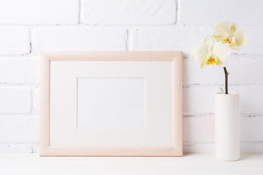 Wooden landscape frame mockup with soft yellow orchid in vase