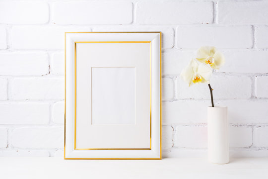 Gold decorated frame mockup with soft yellow orchid in vase