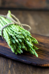 Hip of asparagus laying on wooden board.