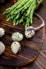 Asparagus and quail eggs on wooden board.