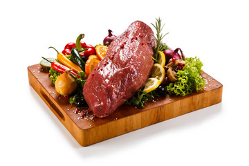 Fresh raw beef with vegetables on cutting board isolated on white