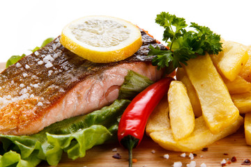 Grilled salmon with french fries on wooden desk on white background