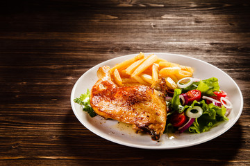 Roast chicken leg with french fries on wooden table