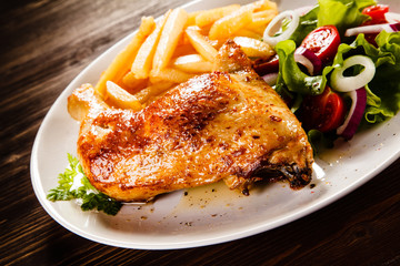 Roast chicken leg with french fries on wooden table
