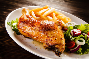 Roast chicken leg with french fries on wooden table