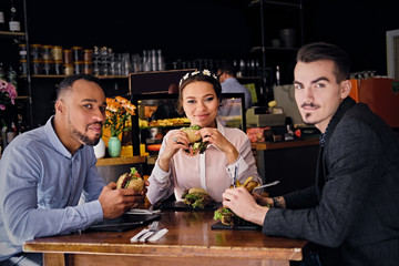 Three people eats sandwiches.