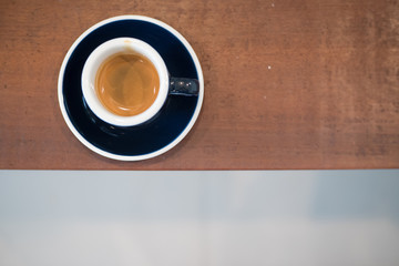 Blue cup of espresso coffee on wood table.