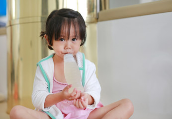 Cute little girl using straw to drink honeydew from bottle.