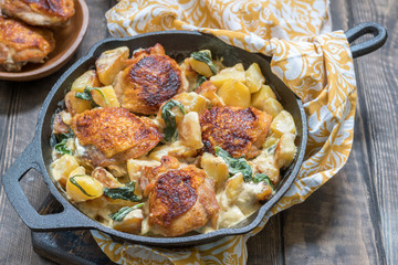 Roast chicken, potatoes and spinach with creamy sauce in a frying pan