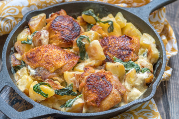 Roast chicken, potatoes and spinach with creamy sauce in a frying pan