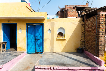 Indian poor house courtyard with yellow walls and a blue door