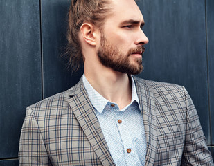 portrait of sexy handsome fashion male model man dressed in elegant checkered suit .posing near dark blue wall in the street background