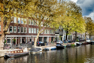 Fototapeta na wymiar Sunny spring day in Amsterdam. Canal view with boats and bicycles, Netherlands