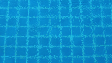 Rain drops on blue water swimming pool