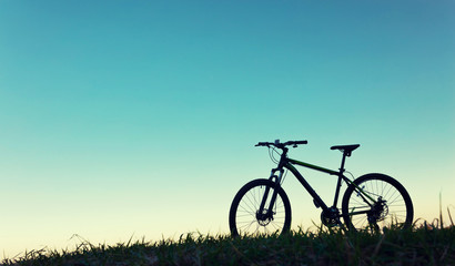 Fototapeta na wymiar Mountain bike. Bicycle grass sky silhouette