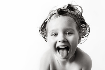 little girl with foam on the head laughs and shows tongue black and white photo
