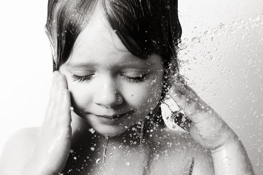 the little girl in the bathroom under running water, beautiful drops the person black and white photo