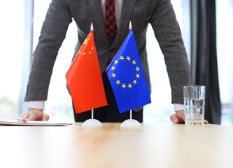 Chinese flag and flag of European Union with businessman near by.