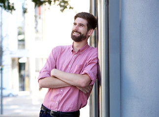 attractive man leaning on wall with arms crossed outside