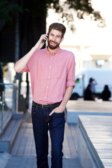Fototapeta premium cheerful man walking on sidewalk and talking on mobile phone