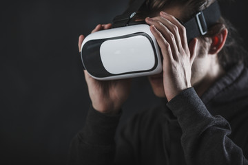 man standing in virtual reality helmet before dark background