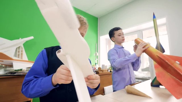 Elementary school boys assembling constructor models of the plane and the model of the rocket. 4K.