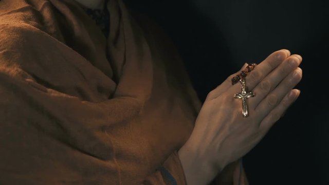Young woman praying with rosary in hand