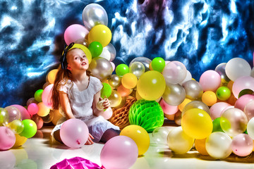 Fototapeta na wymiar Girl is sitting on the floor surrounded by balloons