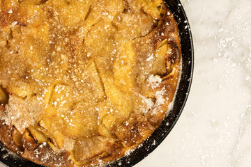 Apple puff pancake pie sprinkled with sugar, with copyspace