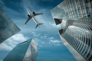 Rolgordijnen Vliegtuig vliegt over moderne glazen en stalen kantoorgebouwen in de buurt © Andrii IURLOV