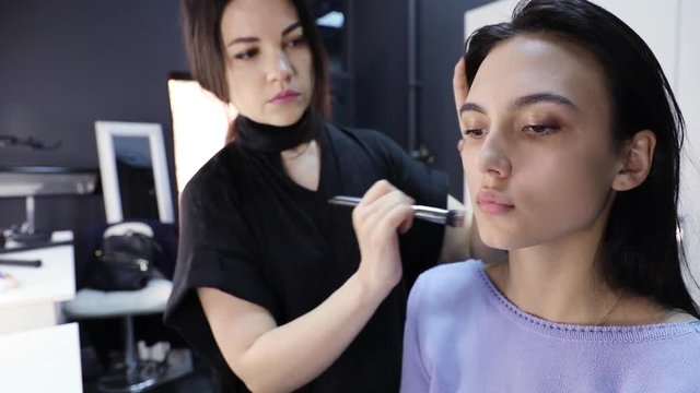 make up artist doing professional make up and working with young beautiful woman